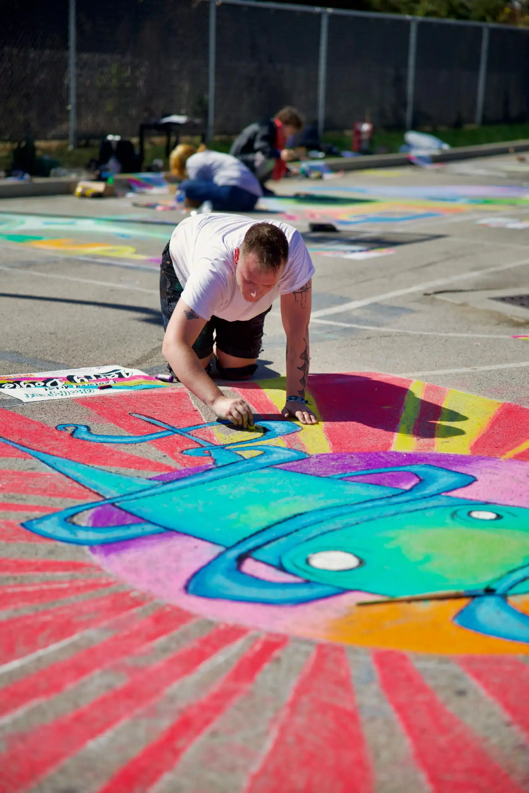 man coloring in chalk art on the street